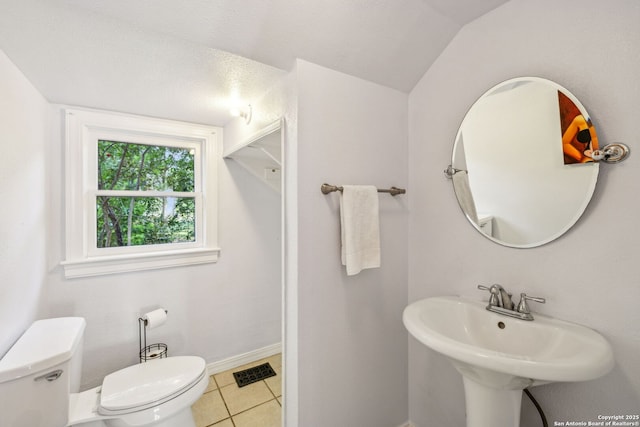 half bathroom with visible vents, tile patterned flooring, a sink, baseboards, and toilet