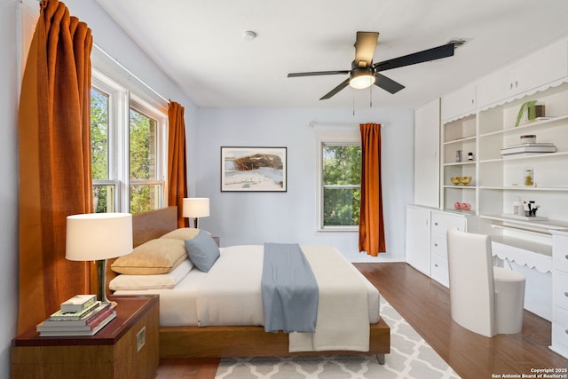 bedroom featuring dark wood-type flooring, a ceiling fan, and multiple windows
