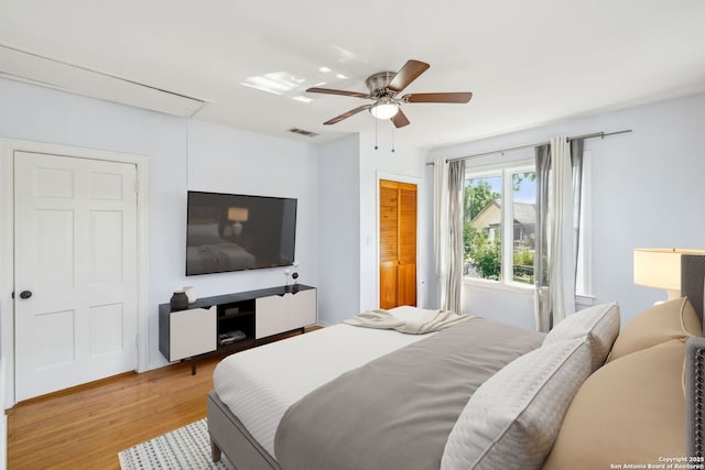 bedroom with ceiling fan, visible vents, attic access, and light wood-style floors