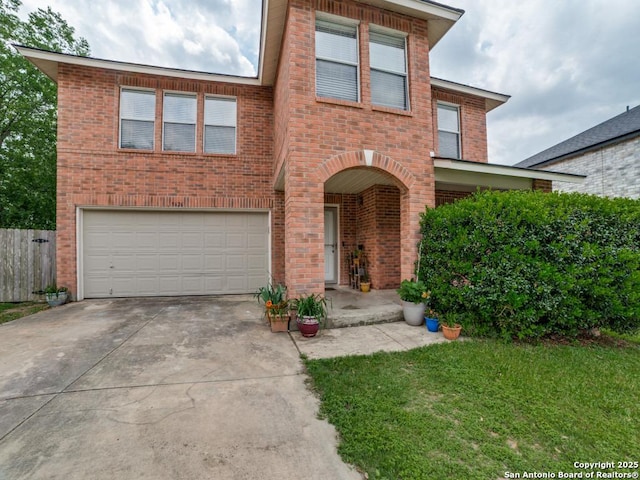 traditional home with driveway, a front yard, a garage, brick siding, and fence