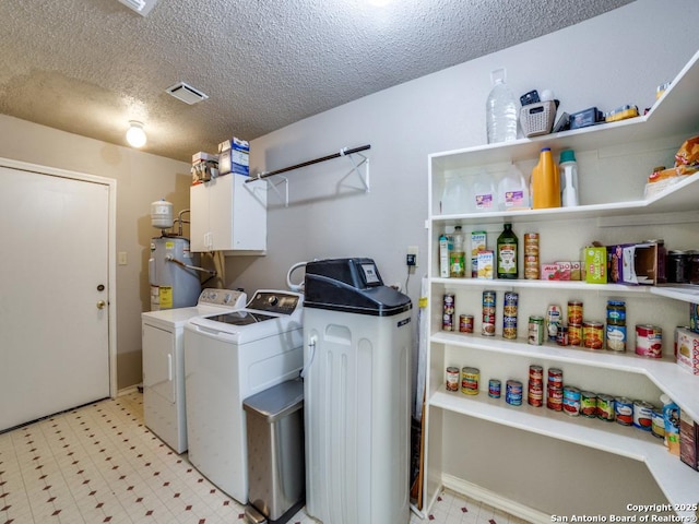 laundry area with visible vents, washer and dryer, light floors, a textured ceiling, and water heater
