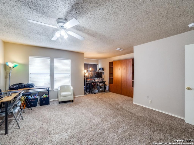 carpeted home office featuring a textured ceiling, ceiling fan, and baseboards