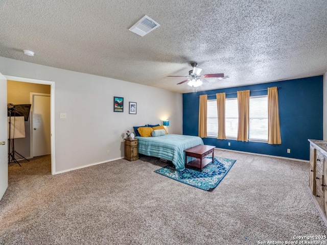 carpeted bedroom featuring a ceiling fan, a textured ceiling, visible vents, and baseboards