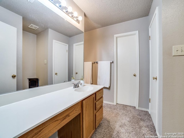 bathroom featuring vanity, baseboards, a textured ceiling, and visible vents