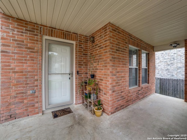 doorway to property featuring brick siding and covered porch