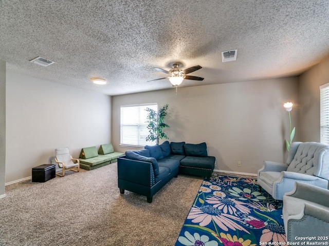 carpeted living room with baseboards, a ceiling fan, a textured ceiling, and visible vents