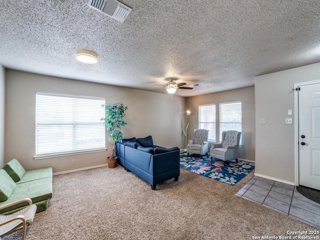 carpeted living room with baseboards, ceiling fan, a textured ceiling, and visible vents