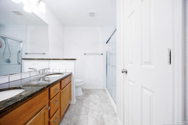bathroom with a sink, double vanity, toilet, a shower with door, and visible vents