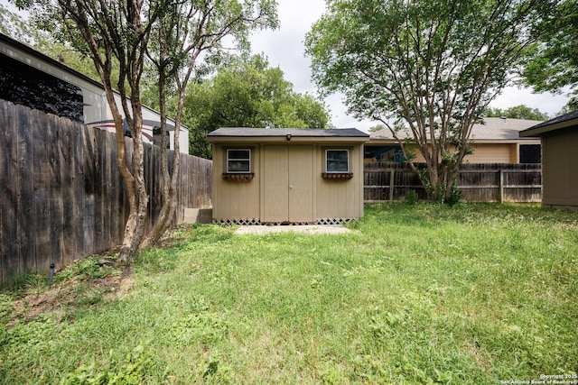 view of yard with a storage unit, a fenced backyard, and an outbuilding