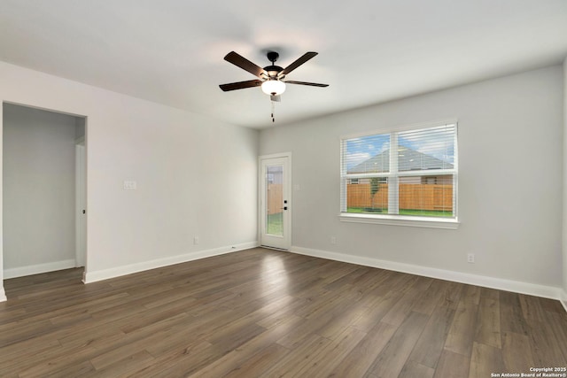 unfurnished room with baseboards, a ceiling fan, and dark wood-style floors