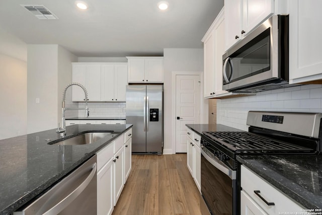 kitchen with visible vents, appliances with stainless steel finishes, a sink, white cabinets, and light wood-style floors