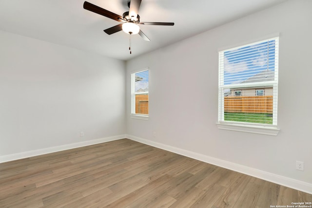 empty room featuring a ceiling fan, baseboards, and light wood-type flooring