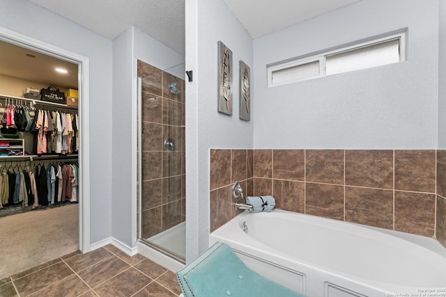bathroom with tile patterned flooring, a bath, a stall shower, and a spacious closet