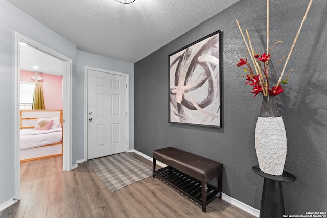 entryway featuring a textured ceiling, baseboards, and wood finished floors
