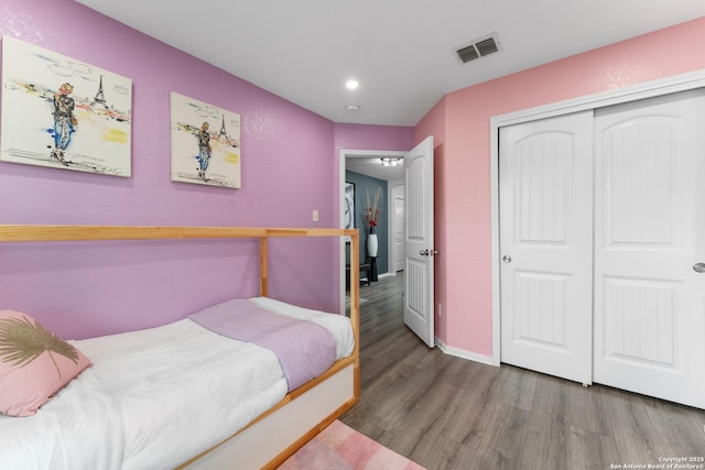 bedroom with recessed lighting, baseboards, wood finished floors, visible vents, and a closet
