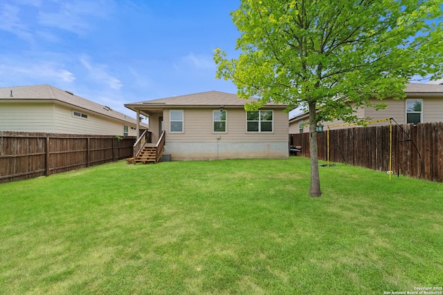 rear view of house featuring a yard and a fenced backyard