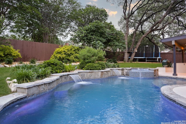 view of pool with a fenced backyard, a fenced in pool, a trampoline, and a lawn