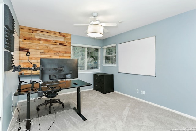 carpeted office with wooden walls, a ceiling fan, and baseboards