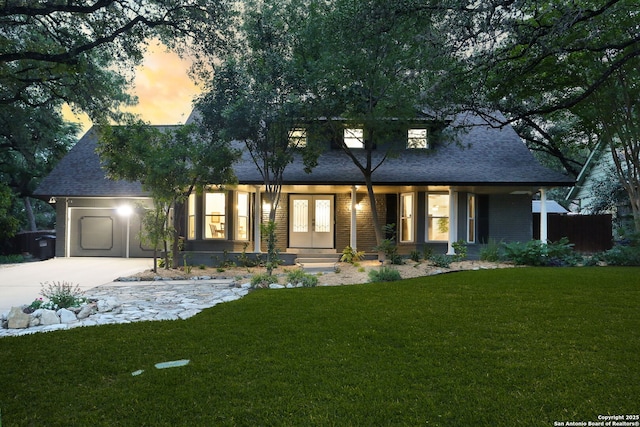 view of front of property featuring french doors, a front yard, roof with shingles, a garage, and concrete driveway