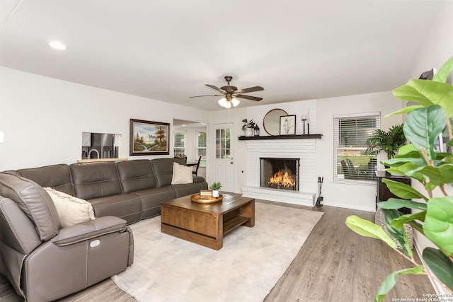 living room with a brick fireplace, a ceiling fan, baseboards, recessed lighting, and wood finished floors