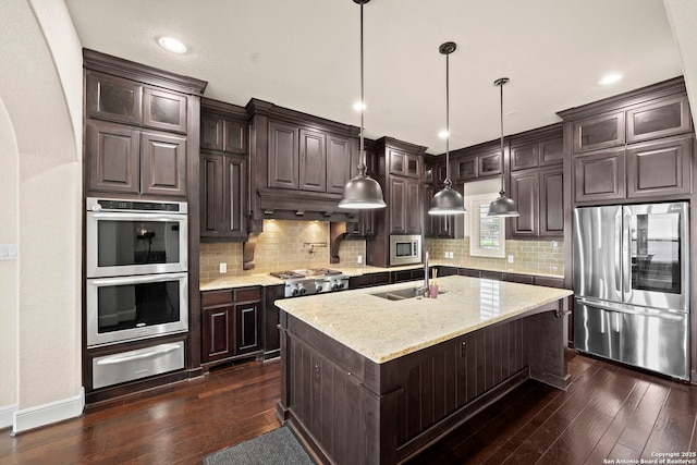 kitchen featuring dark brown cabinetry, a sink, dark wood finished floors, stainless steel appliances, and a warming drawer