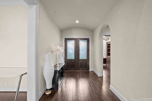 entrance foyer featuring baseboards, arched walkways, dark wood finished floors, and vaulted ceiling