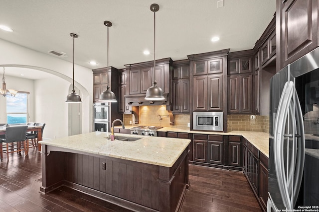 kitchen featuring visible vents, arched walkways, a sink, dark wood finished floors, and stainless steel appliances