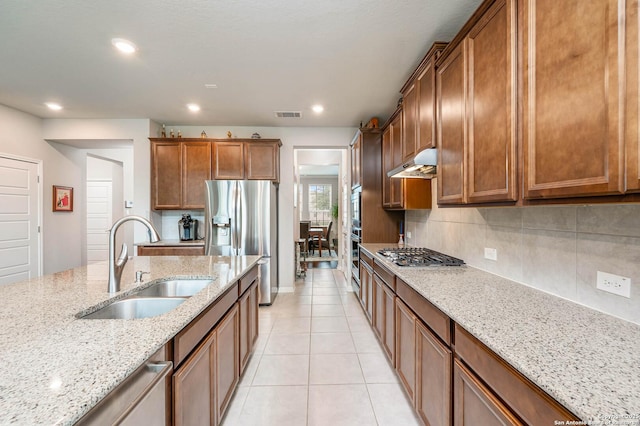 kitchen featuring visible vents, under cabinet range hood, tasteful backsplash, a sink, and stainless steel appliances