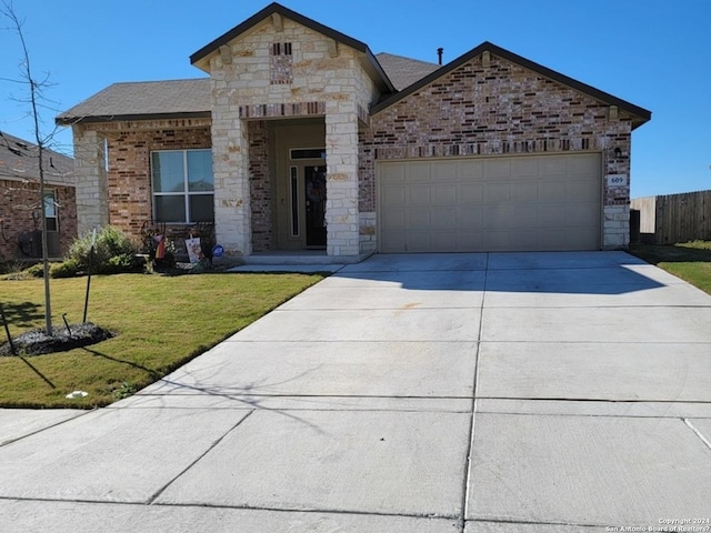 view of front of house with a garage, fence, a front lawn, concrete driveway, and stone siding