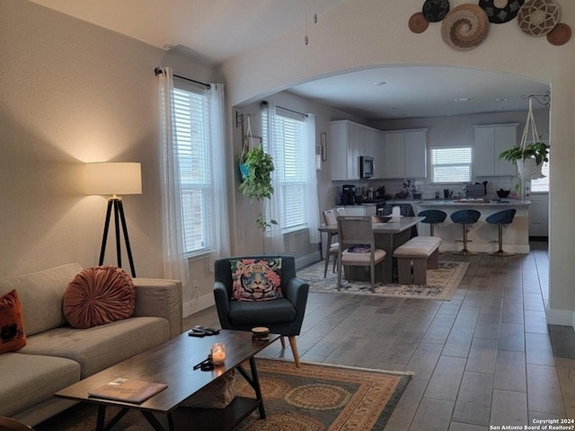 living room with baseboards, arched walkways, and wood finished floors