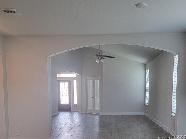 spare room with baseboards, ceiling fan, lofted ceiling, and visible vents