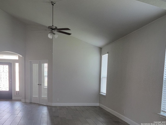empty room with arched walkways, ceiling fan, vaulted ceiling, and a healthy amount of sunlight