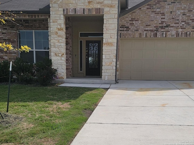 doorway to property with an attached garage, stone siding, brick siding, concrete driveway, and a yard