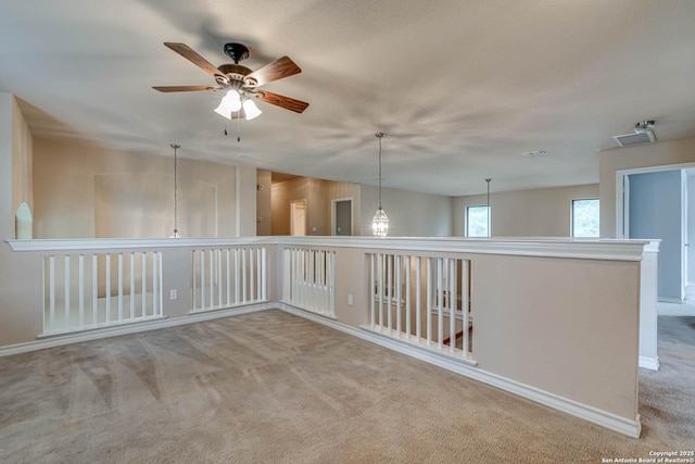unfurnished room with carpet floors, baseboards, a ceiling fan, and visible vents