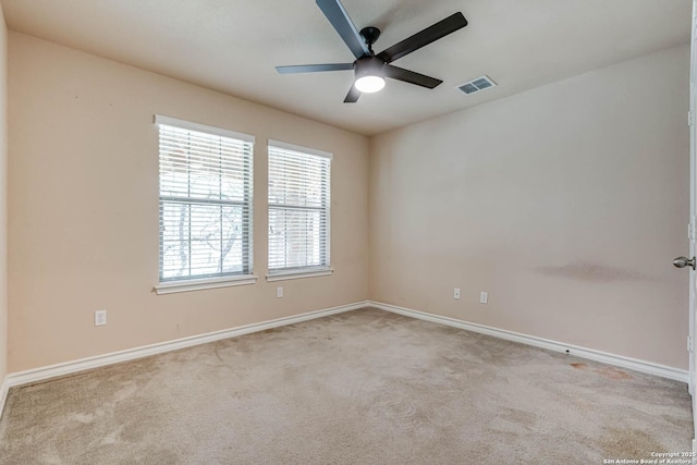 carpeted spare room featuring baseboards, a ceiling fan, and visible vents