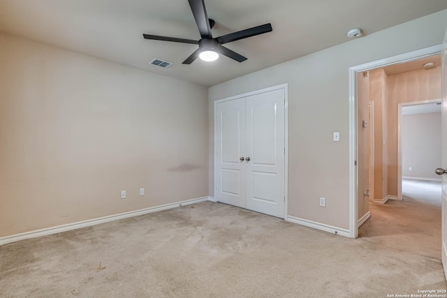 unfurnished bedroom featuring a ceiling fan, light colored carpet, visible vents, baseboards, and a closet