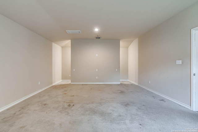 empty room with baseboards, visible vents, and light carpet
