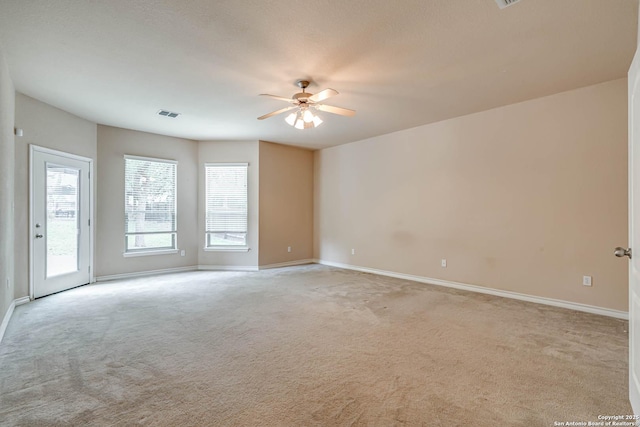 spare room with a ceiling fan, baseboards, visible vents, and light carpet