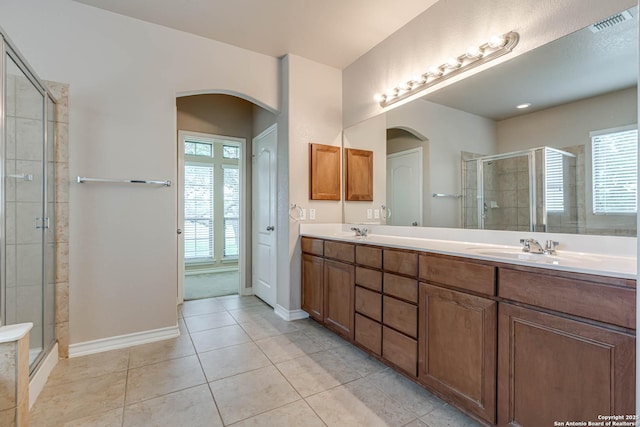 bathroom with double vanity, tile patterned flooring, a shower stall, a sink, and baseboards