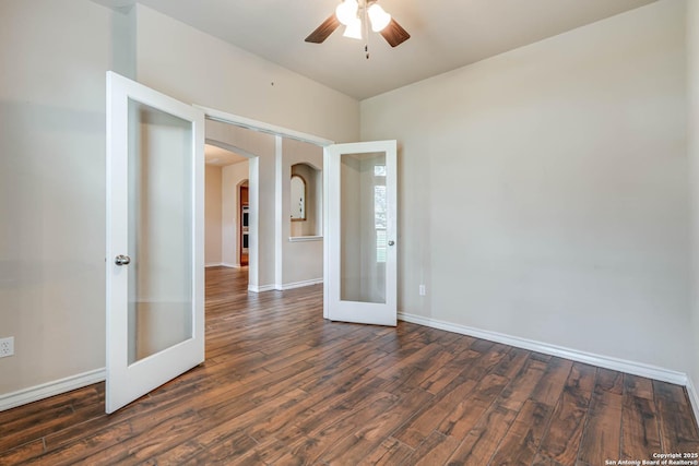 empty room featuring a ceiling fan, french doors, arched walkways, wood finished floors, and baseboards