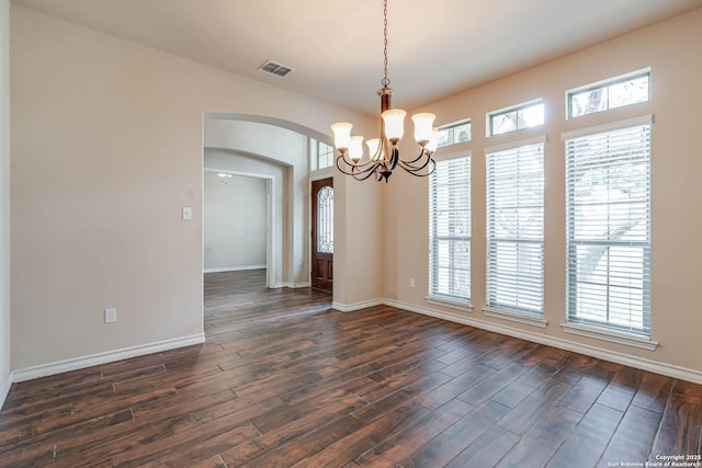 unfurnished room with visible vents, arched walkways, dark wood-style flooring, and a chandelier