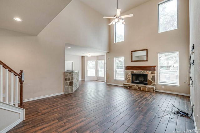 unfurnished living room featuring baseboards, plenty of natural light, dark wood-type flooring, and a fireplace