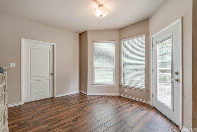 empty room featuring baseboards and dark wood-style flooring