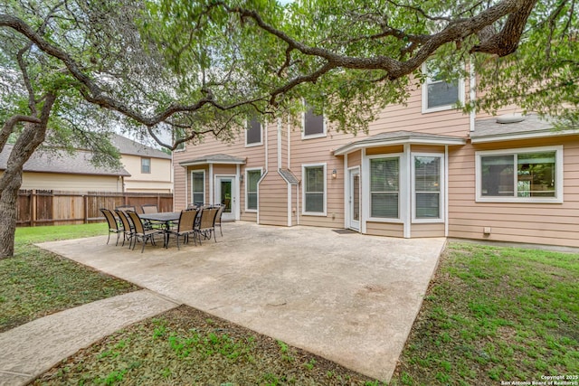 back of property featuring a lawn, a patio, and fence
