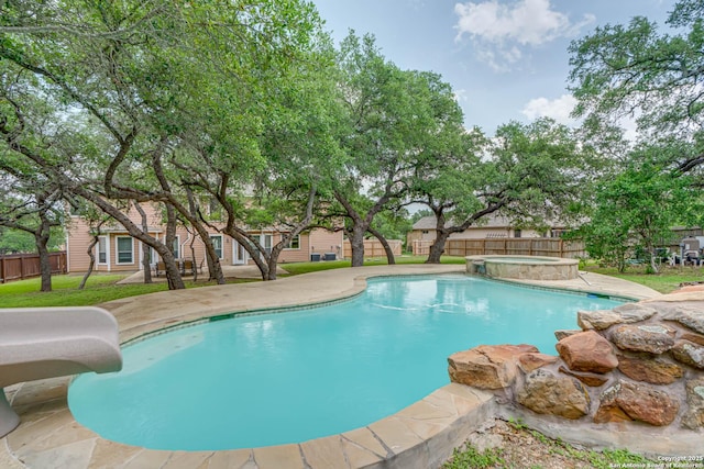 view of pool featuring a patio, a fenced backyard, a lawn, a water slide, and a pool with connected hot tub