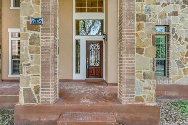entrance to property featuring a porch and stone siding