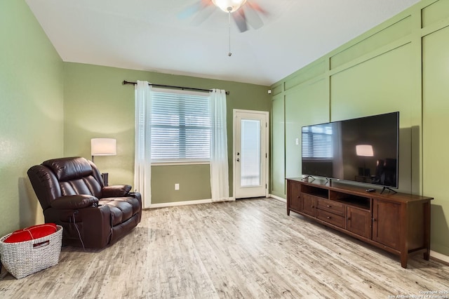living area featuring baseboards, a ceiling fan, and light wood-type flooring