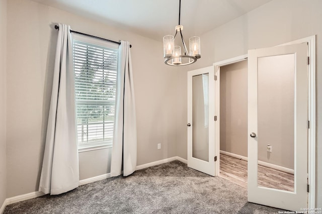 interior space featuring carpet flooring, a chandelier, a healthy amount of sunlight, and french doors