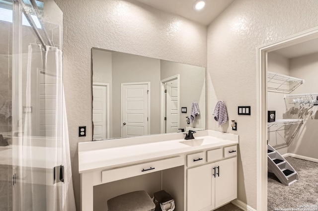 bathroom with a stall shower, vanity, baseboards, a textured wall, and recessed lighting