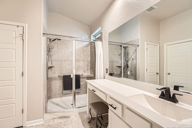 full bathroom featuring visible vents, vanity, vaulted ceiling, and a shower stall